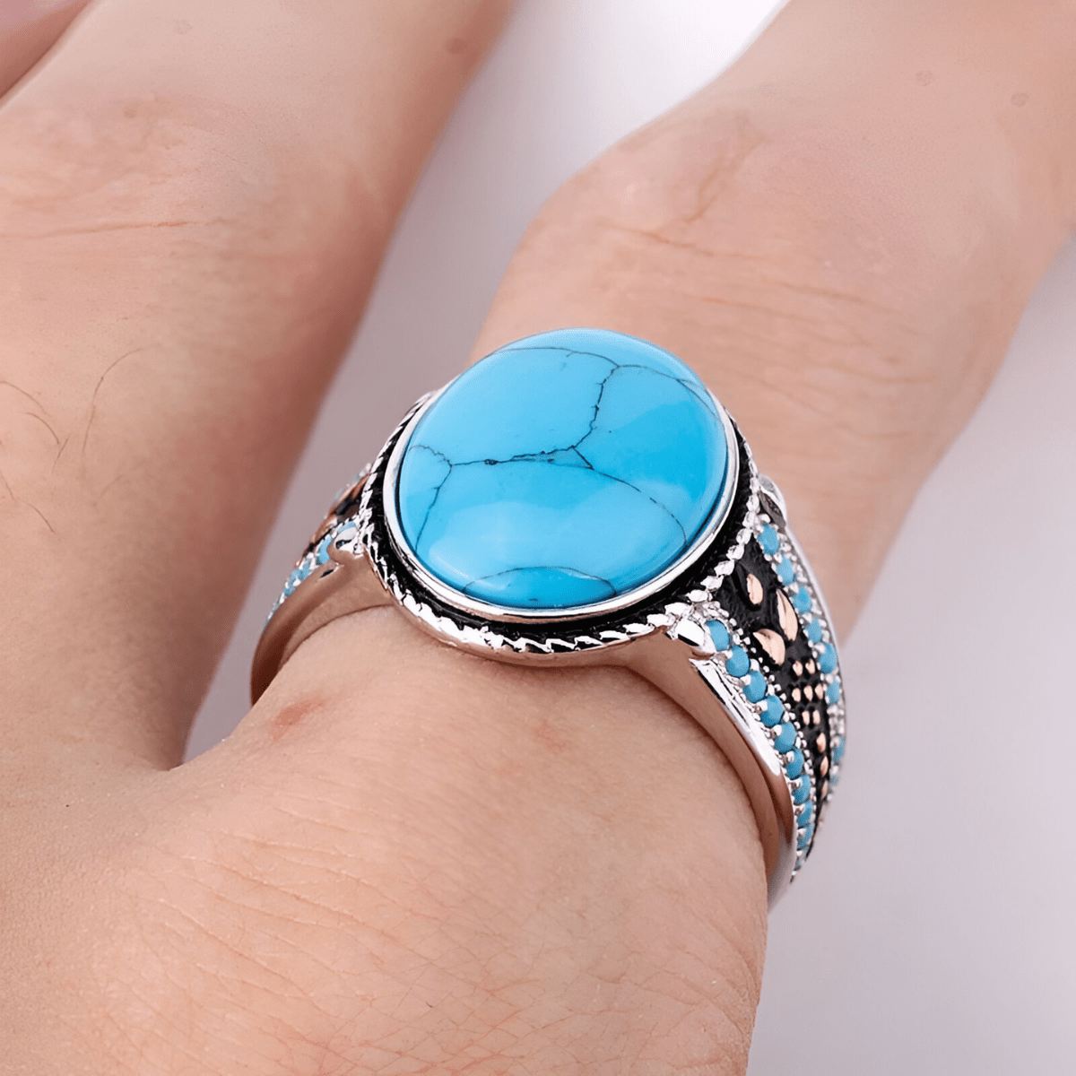 Bague turquoise cabochon avec pierre ovale bombée montée sur anneau argenté orné de détails noirs et bleus