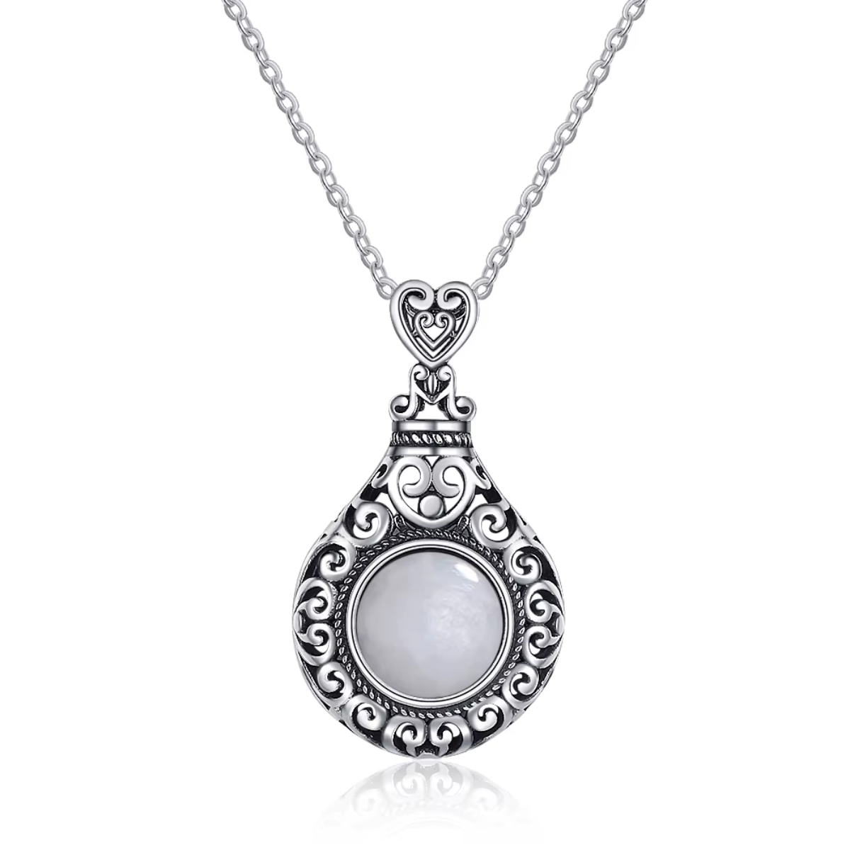 Un collier avec une pierre de lune blanche sertie dans un pendentif en argent finement orné de motifs en volutes élégantes.