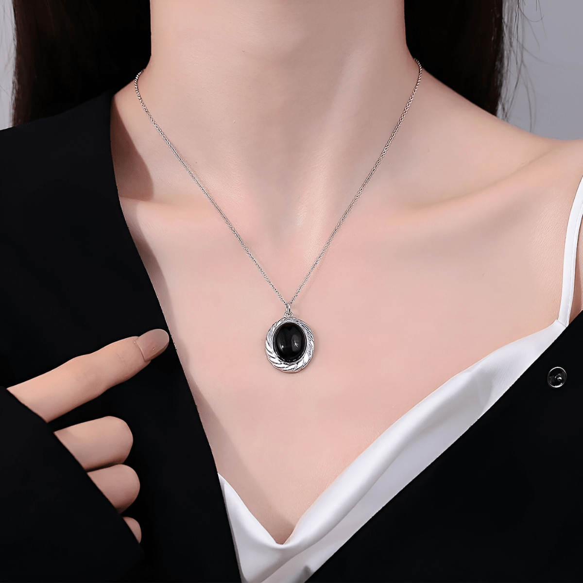 Collier obsidienne porté avec pendentif rond noir encadré de motifs argentés sur chaîne fine en argent