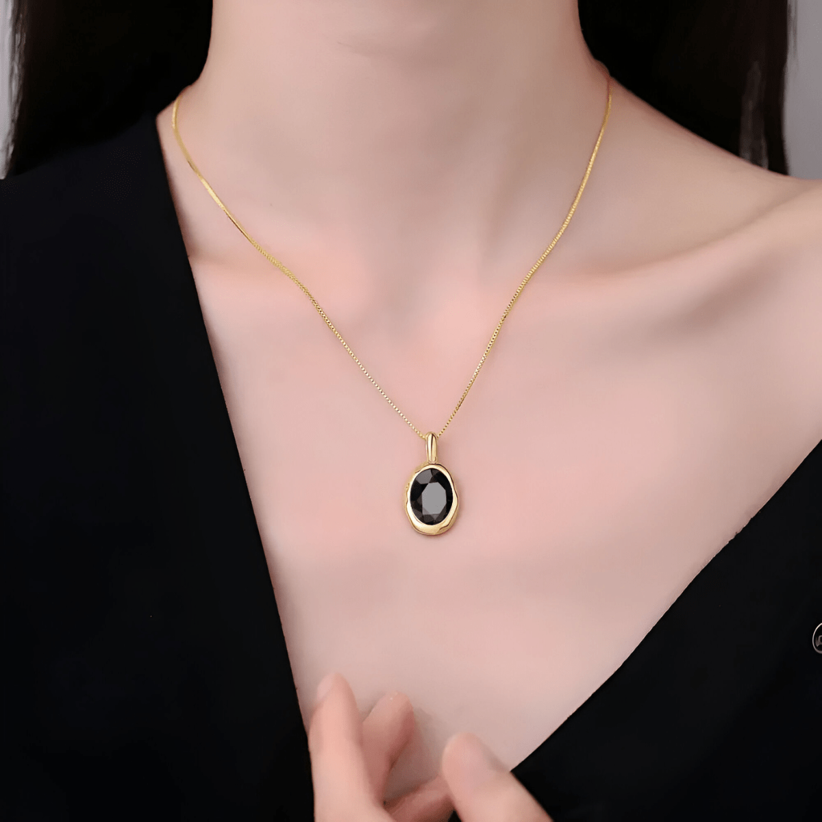 Collier obsidienne porté au cou avec pendentif ovale doré et pierre noire facettée au centre