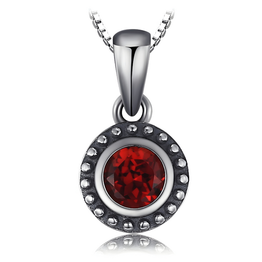Une chaîne argentée soutient un pendentif rond en pierre naturelle de grenat facettée dans un sertissage argenté texturé, collier Grenat au style minimaliste