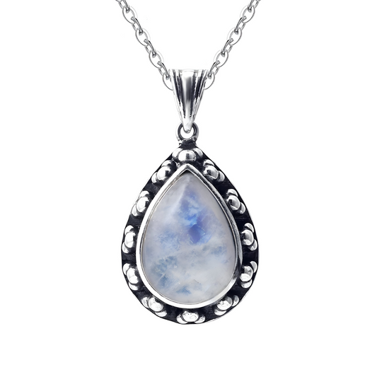 Un collier avec une pierre de lune en forme de goutte, sertie dans un pendentif en argent orné de petits motifs ronds martelés.