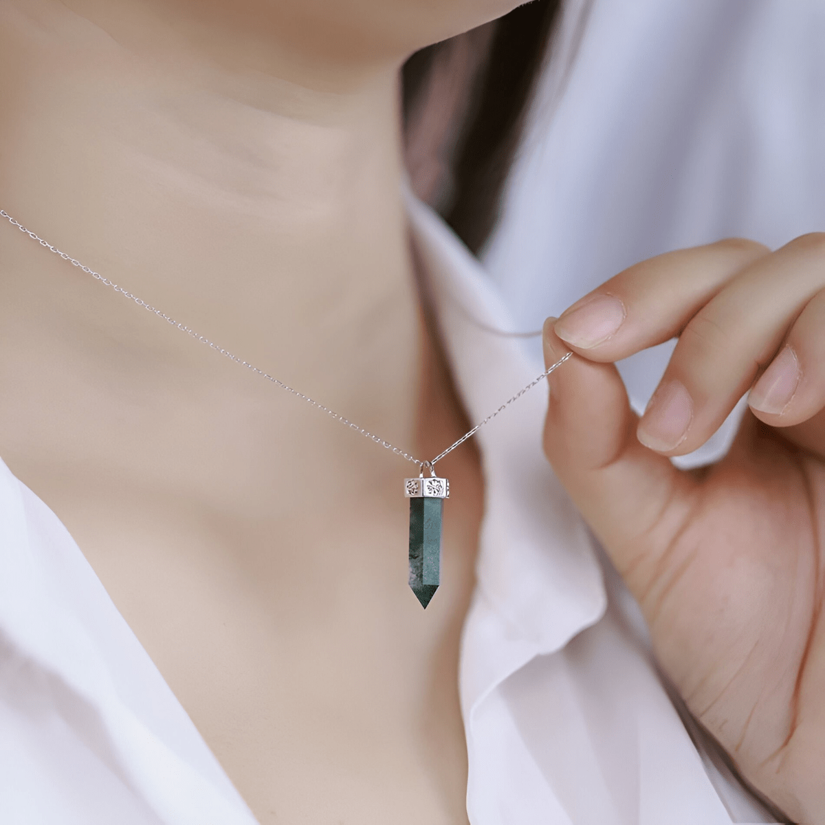 Collier malachite avec pendentif pointe verte et monture argentée tenu à la main sur chaîne fine