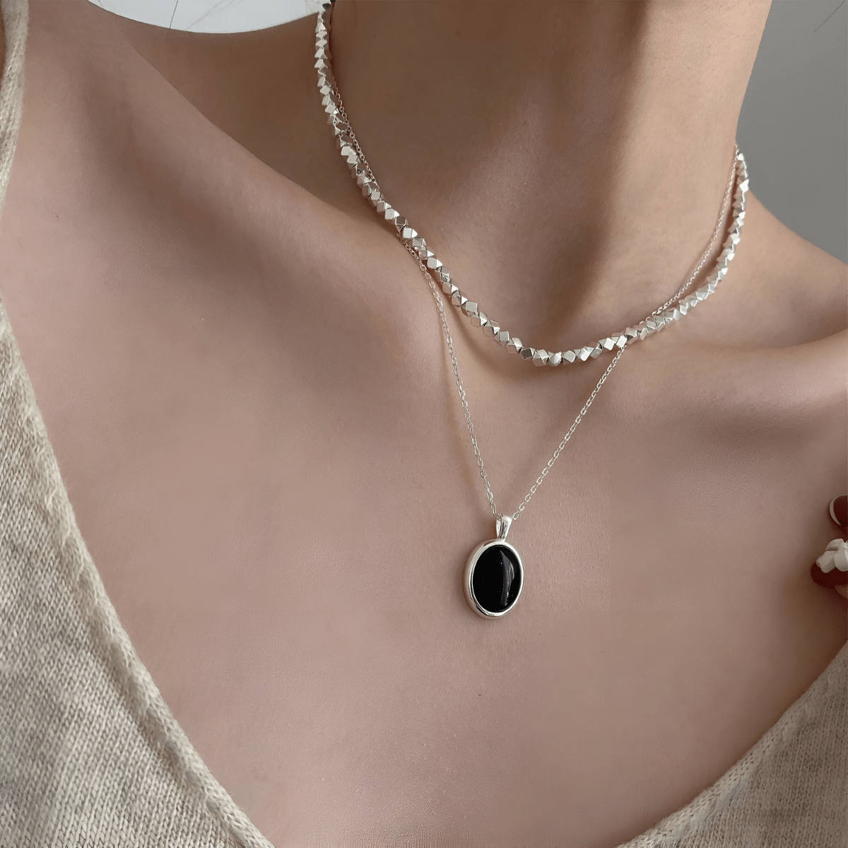 Collier obsidienne porté avec pendentif ovale noir serti dans un cadre argenté sur chaîne fine en argent